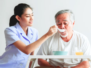 beautiful nurse feeding the senior man